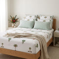 A premium lifestyle bedroom scene featuring the bedding set fully styled on a neatly made bed, showing the white cotton bedsheet with the green palm and grey elephant hand block print pattern, along with the matching green-and-white chevron pillowcases. Front three-quarter angle view, soft natural daylight, neutral modern Australian home decor, elegant aesthetic.