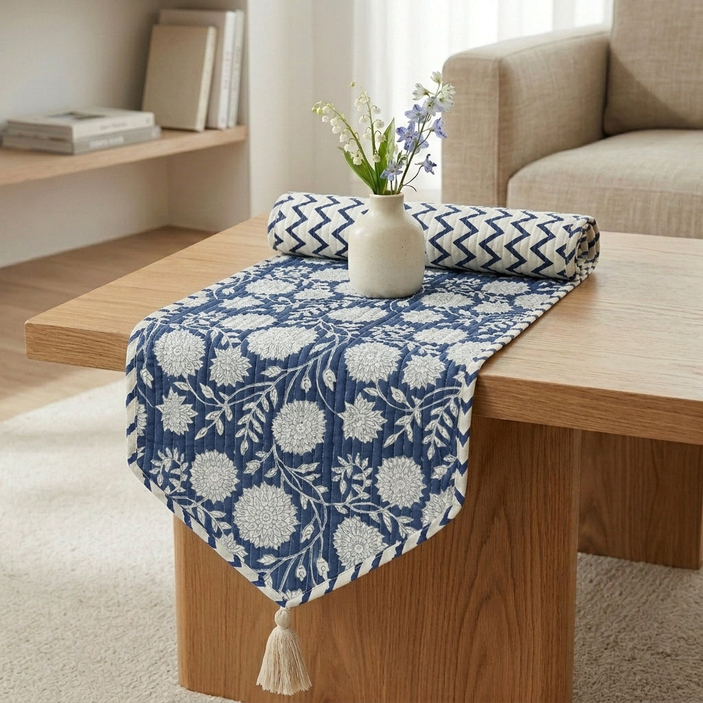 Reversible cotton table runner styled on coffee table showing midnight blue botanical floral pattern on top and navy chevron pattern on the fold